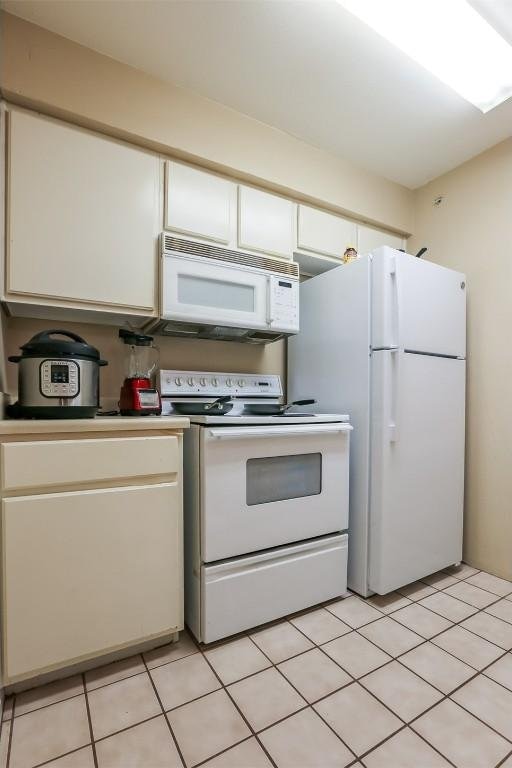 501 W 26th St Unit 312, Austin, TX 78705 - kitchen featuring white appliances, white cabinets, light countertops, and light tile patterned floors