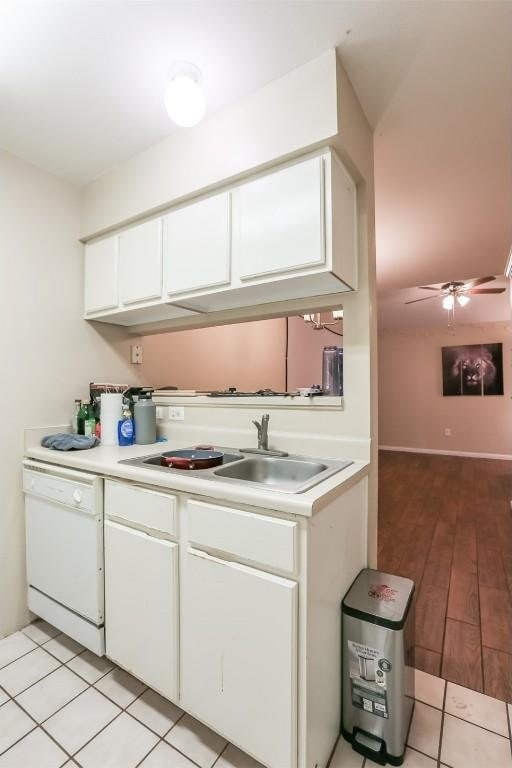 kitchen featuring light countertops, white cabinets, white dishwasher, and a sink