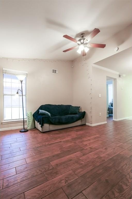living area featuring baseboards, visible vents, hardwood / wood-style flooring, and ceiling fan