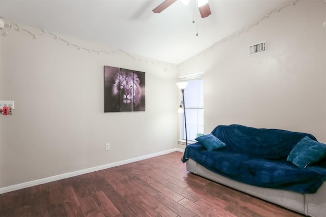 living area with ceiling fan, visible vents, vaulted ceiling, baseboards, and wood finished floors