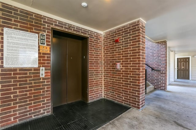 doorway to property with elevator and brick siding