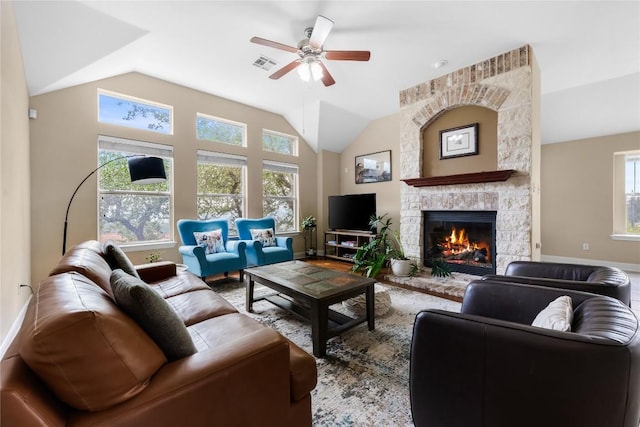 living room featuring ceiling fan, a stone fireplace, visible vents, vaulted ceiling, and baseboards