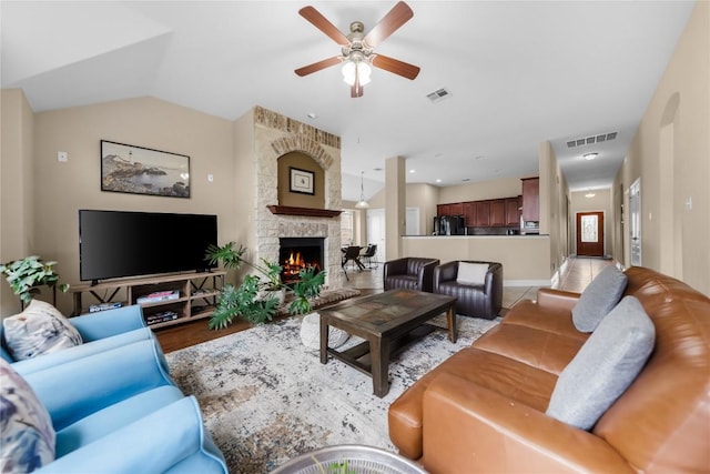 living room with a ceiling fan, visible vents, a stone fireplace, and plenty of natural light