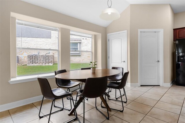 dining area with light tile patterned floors, vaulted ceiling, and baseboards