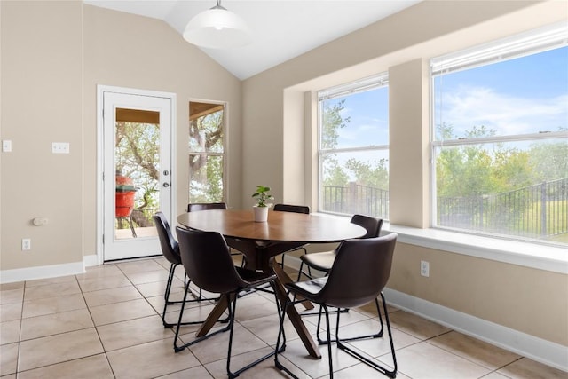 dining space with lofted ceiling, light tile patterned flooring, and baseboards