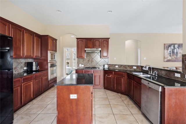 kitchen with stainless steel appliances, backsplash, arched walkways, and a sink
