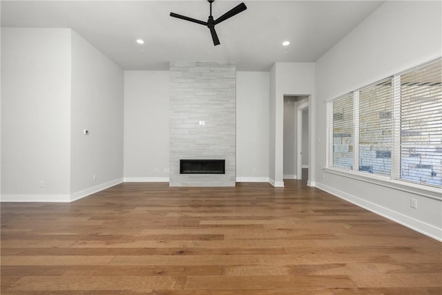 unfurnished living room featuring baseboards, ceiling fan, a tile fireplace, and light wood-style flooring