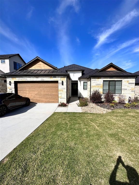 14720 Marchesa Dr, Bee Cave, TX 78738 - view of front of house featuring stone siding, an attached garage, driveway, a front lawn, and a standing seam roof
