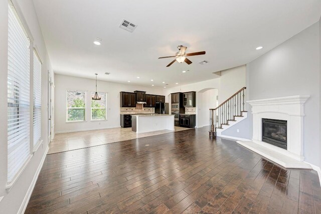 3909 Vinalopo Dr, Austin, TX 78738 - unfurnished living room featuring a glass covered fireplace, a ceiling fan, arched walkways, baseboards, and recessed lighting