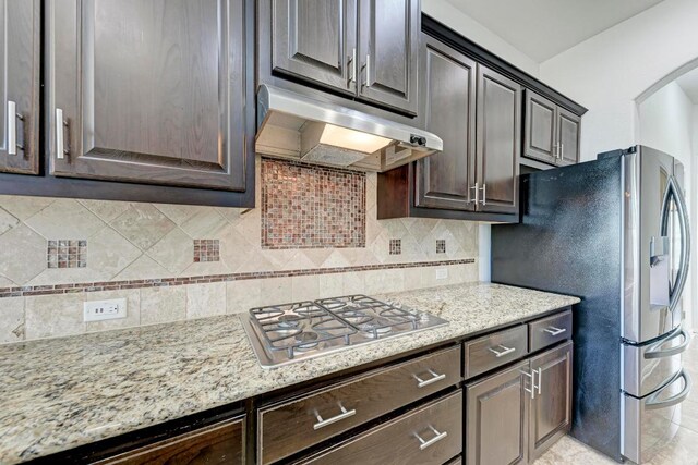 3909 Vinalopo Dr, Austin, TX 78738 - kitchen with under cabinet range hood, appliances with stainless steel finishes, dark brown cabinets, arched walkways, and backsplash