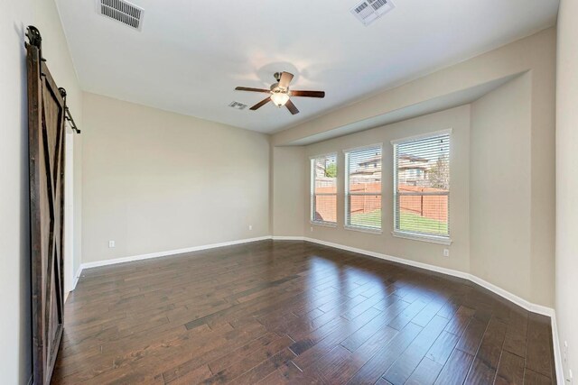 3909 Vinalopo Dr, Austin, TX 78738 - spare room featuring a barn door, ceiling fan, baseboards, and dark wood-type flooring