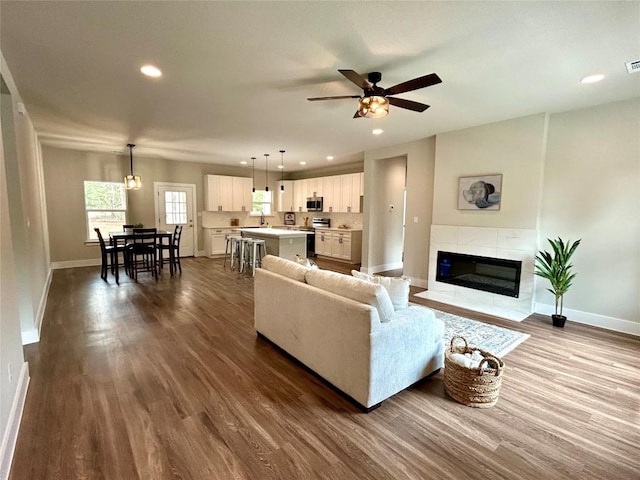 128 Heleakala Dr, Bastrop, TX 78602 - living room with baseboards, ceiling fan, recessed lighting, dark wood-type flooring, and a tiled fireplace