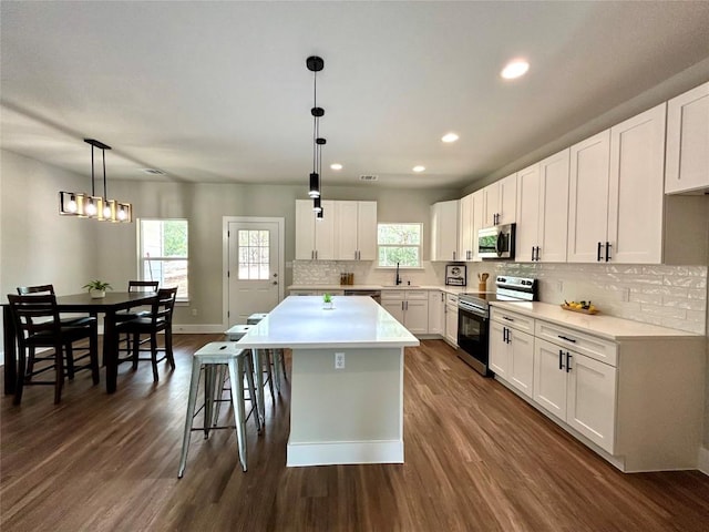 128 Heleakala Dr, Bastrop, TX 78602 - kitchen featuring dark wood-style floors, a center island, tasteful backsplash, a sink, and appliances with stainless steel finishes