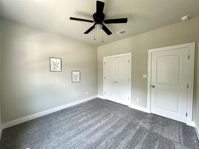 128 Heleakala Dr, Bastrop, TX 78602 - unfurnished bedroom with ceiling fan, dark colored carpet, baseboards, visible vents, and a closet