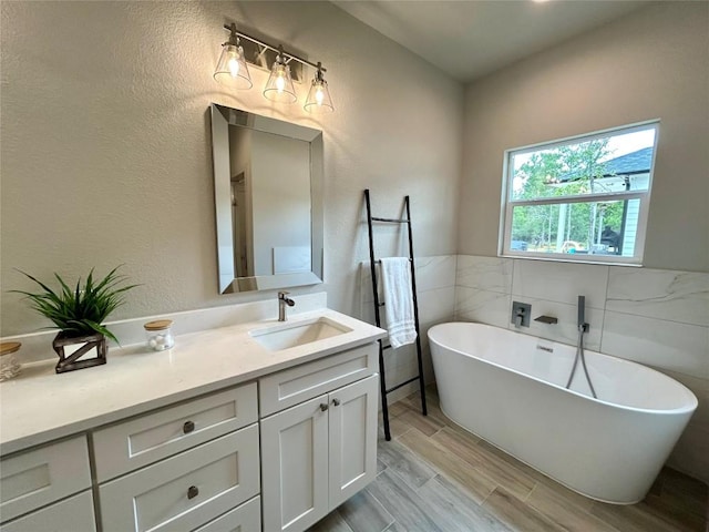 128 Heleakala Dr, Bastrop, TX 78602 - bathroom with tile walls, wood tiled floor, a soaking tub, and vanity