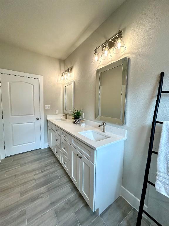 128 Heleakala Dr, Bastrop, TX 78602 - bathroom with a sink, baseboards, double vanity, and wood finished floors