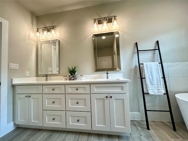 128 Heleakala Dr, Bastrop, TX 78602 - bathroom featuring double vanity, a freestanding bath, a sink, and wood finished floors