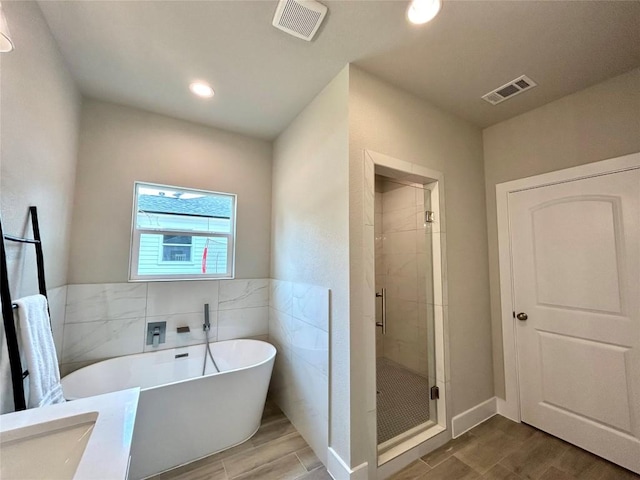 128 Heleakala Dr, Bastrop, TX 78602 - full bath featuring visible vents, a stall shower, wood finished floors, and a soaking tub