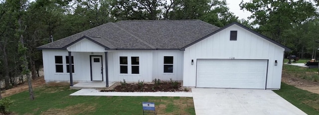 128 Heleakala Dr, Bastrop, TX 78602 - ranch-style house with a shingled roof, an attached garage, board and batten siding, a front yard, and concrete driveway