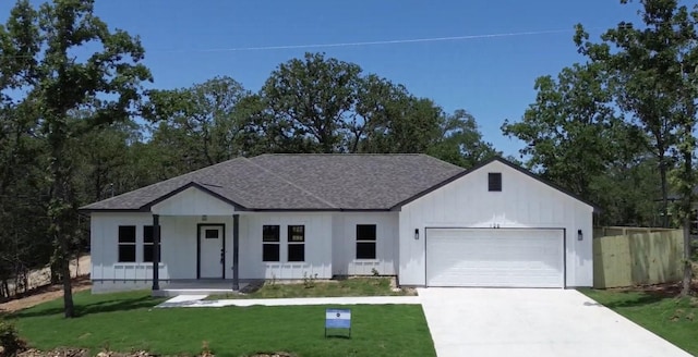 128 Heleakala Dr, Bastrop, TX 78602 - modern farmhouse with a porch, an attached garage, a shingled roof, driveway, and board and batten siding