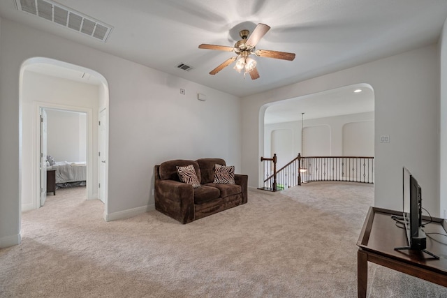 living area featuring arched walkways, visible vents, and ceiling fan