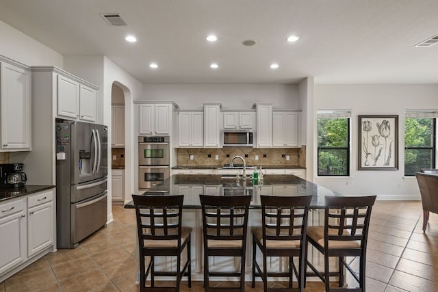 kitchen featuring recessed lighting, arched walkways, decorative backsplash, appliances with stainless steel finishes, and visible vents