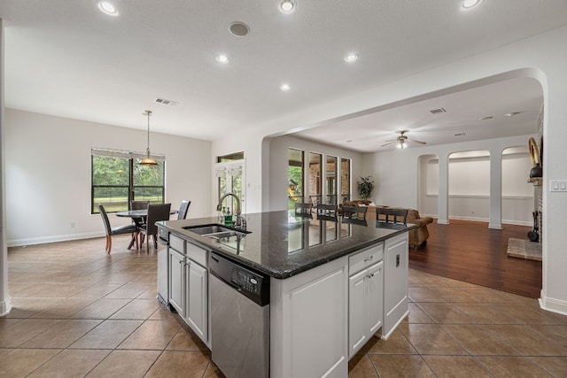 kitchen featuring recessed lighting, a sink, arched walkways, dishwasher, and an island with sink