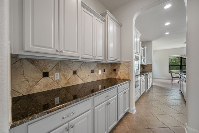 kitchen featuring recessed lighting, arched walkways, tasteful backsplash, light tile patterned floors, and white cabinetry