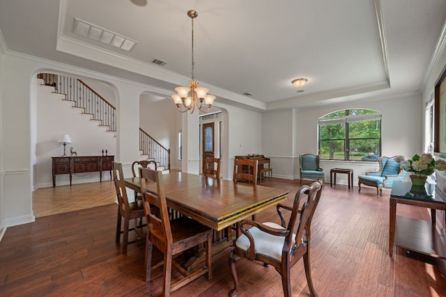 dining room with dark wood-style floors, a chandelier, a tray ceiling, stairs, and visible vents