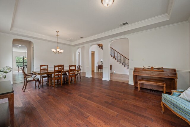 dining area featuring visible vents, arched walkways, wood-type flooring, and a raised ceiling