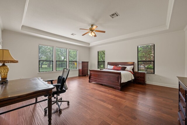 bedroom featuring dark wood-type flooring, visible vents, ornamental molding, and a tray ceiling