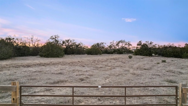 yard at dusk with fence and a rural view
