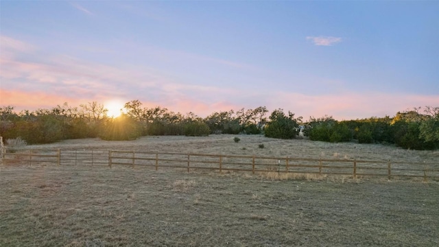 yard at dusk featuring fence and a rural view