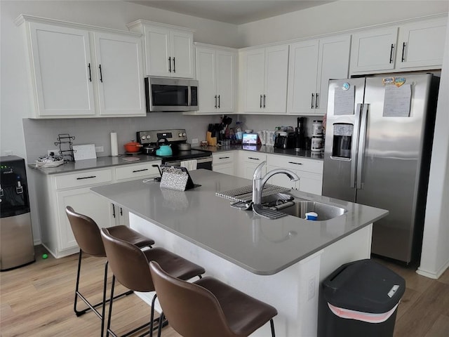kitchen with a kitchen bar, a sink, white cabinetry, and stainless steel appliances