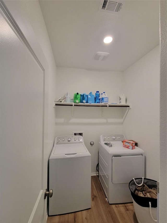 laundry area with wood finished floors, independent washer and dryer, visible vents, and laundry area