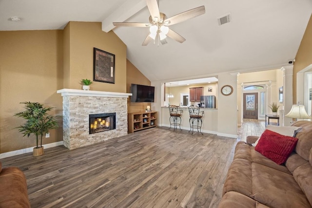 living room featuring a fireplace, ceiling fan, vaulted ceiling with beams, visible vents, and wood finished floors