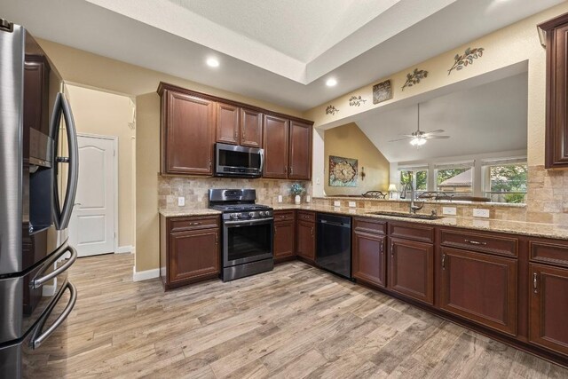 kitchen with lofted ceiling, decorative backsplash, light wood-style flooring, a sink, and appliances with stainless steel finishes