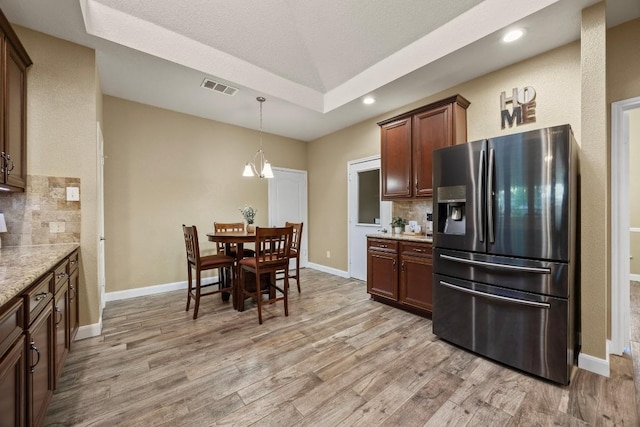 kitchen featuring tasteful backsplash, visible vents, stainless steel refrigerator with ice dispenser, and light wood-style flooring