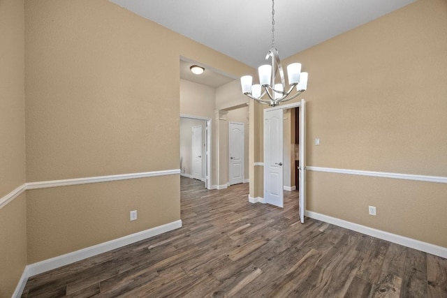 unfurnished dining area with dark wood-style flooring, a notable chandelier, and baseboards