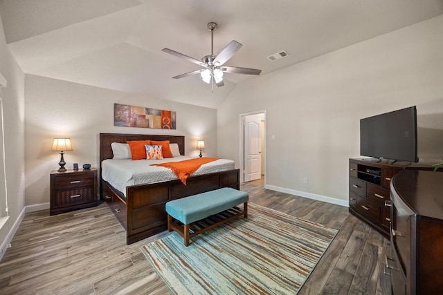 bedroom with visible vents, baseboards, vaulted ceiling, wood finished floors, and a ceiling fan