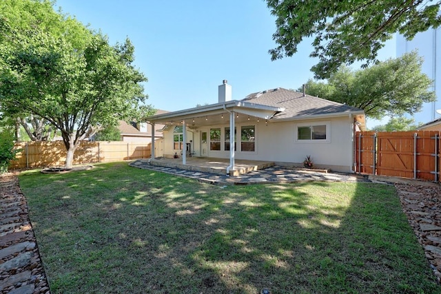 rear view of house with a lawn, a chimney, a fenced backyard, and a patio area