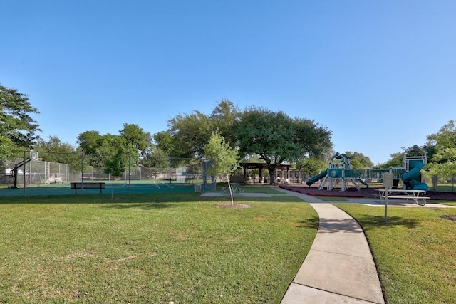 view of home's community featuring a tennis court, fence, playground community, and a lawn