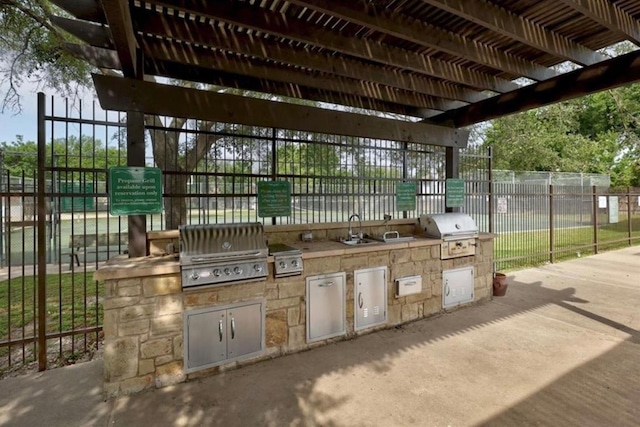 view of patio featuring a sink, an outdoor kitchen, grilling area, and fence