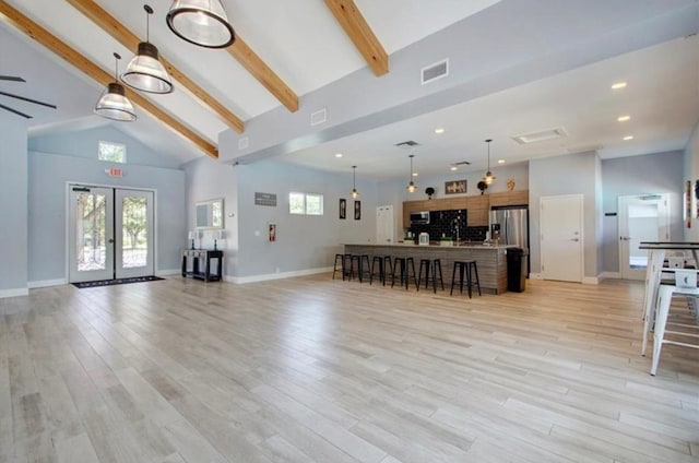 living area with visible vents, lofted ceiling with beams, light wood-style flooring, and french doors
