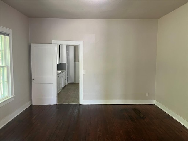 spare room featuring baseboards and dark wood-style flooring