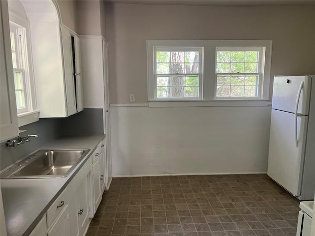 kitchen with white cabinetry, a sink, plenty of natural light, and freestanding refrigerator