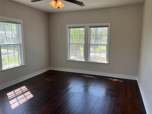 spare room featuring visible vents, hardwood / wood-style flooring, a wealth of natural light, and a ceiling fan