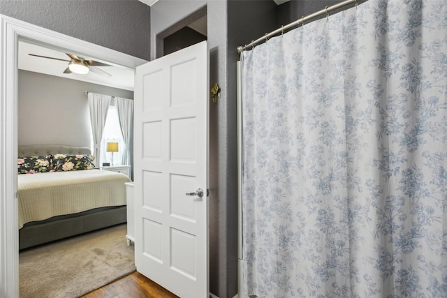 103 Bonham Ln, Paige, TX 78659 - ensuite bathroom featuring a textured wall, wood finished floors, ceiling fan, and curtained shower
