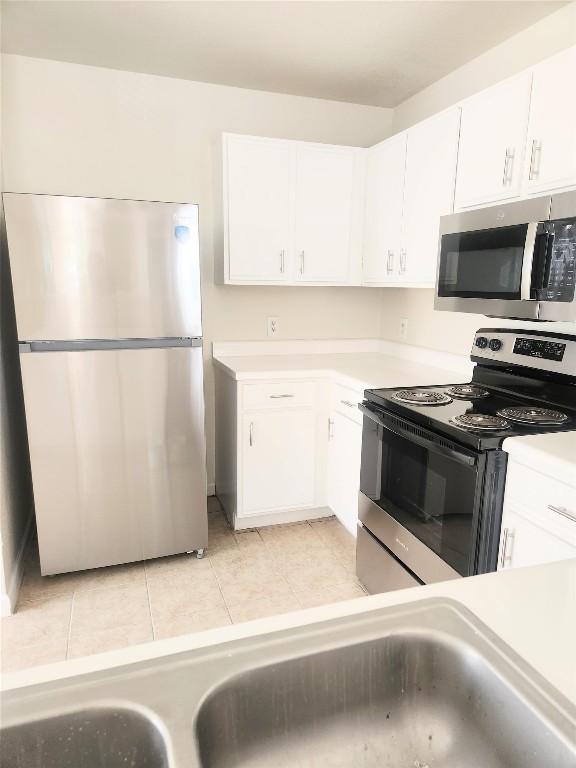 kitchen featuring white cabinets, stainless steel appliances, light countertops, and light tile patterned floors