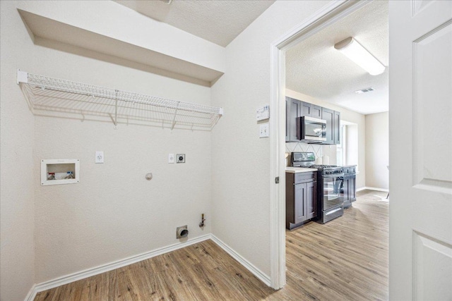 4108 Whitecrest Cv, Round Rock, TX 78681 - laundry room with hookup for a gas dryer, hookup for an electric dryer, hookup for a washing machine, light wood-style floors, and a textured ceiling